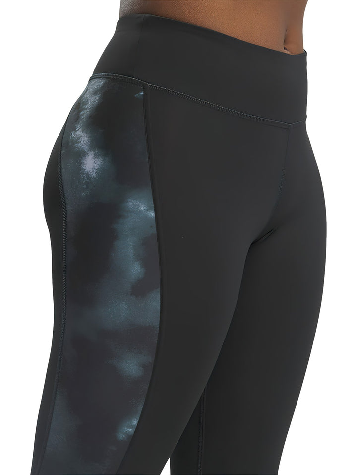 Mujer vistiendo mallas deportivas Reebok negras con detalles laterales brillantes.
