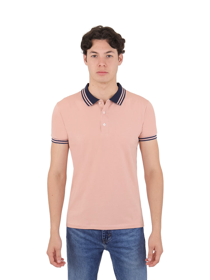 Hombre vistiendo playera polo color salmón con detalles en azul marino en el cuello y puños de las mangas.