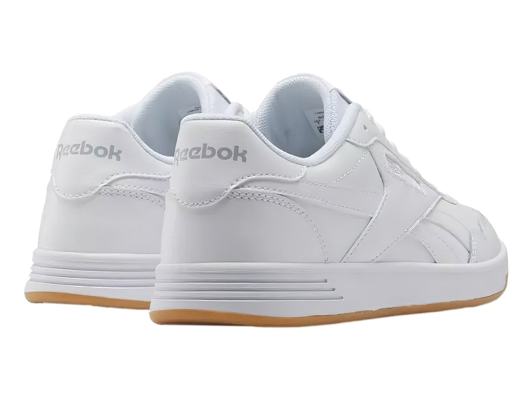 Tenis Reebok Court Advance en color blanco con suela de goma color miel.