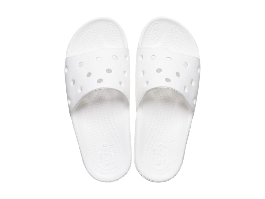 Par de sandalias Crocs Classic Slide V2 en color blanco con perforaciones circulares en la banda superior.