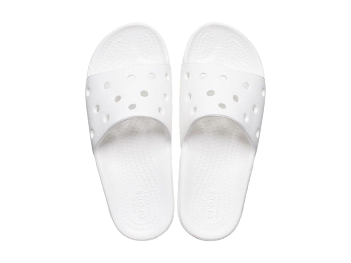 Par de sandalias Crocs Classic Slide V2 en color blanco con perforaciones circulares en la banda superior.