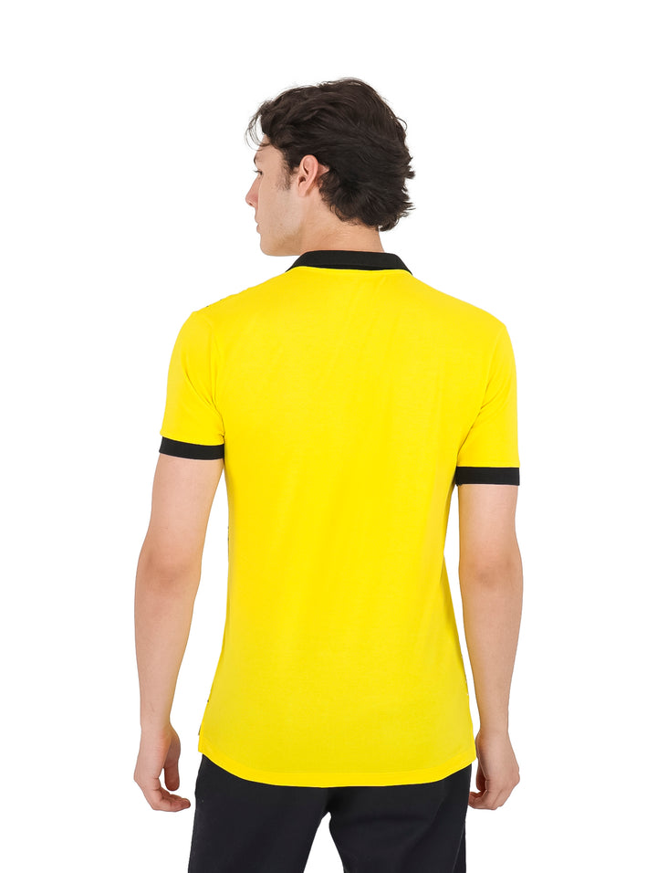 Playera polo amarilla con estampado de puntos negros y detalles en negro en el cuello y mangas.