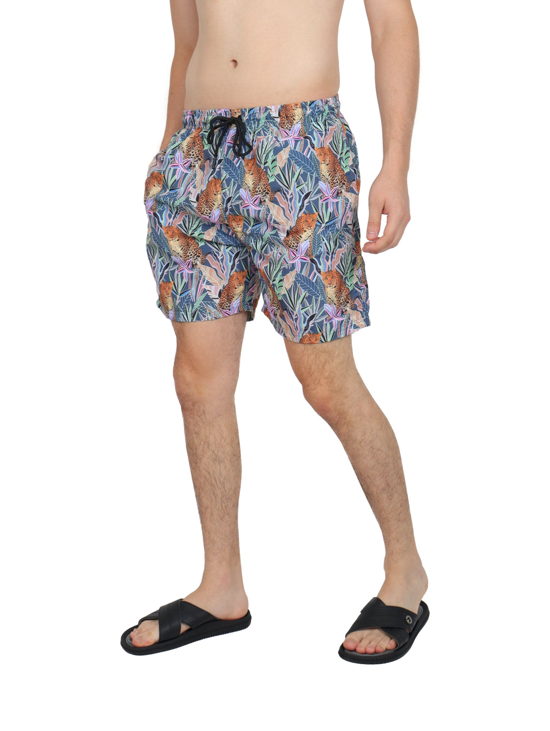 Hombre vistiendo traje de baño corto multicolor con estampado de jaguares y hojas tropicales.