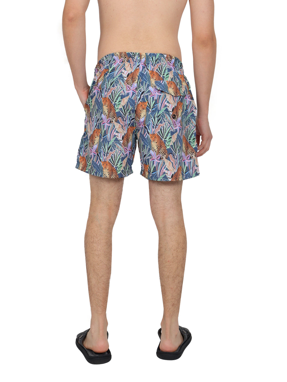 Hombre vistiendo traje de baño corto multicolor con estampado de jaguares y hojas tropicales.