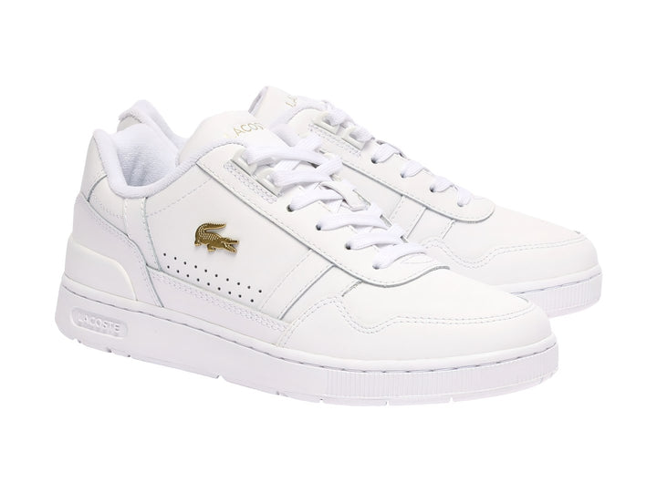 Tenis Lacoste blancos de cuero con logotipo dorado y suela blanca.