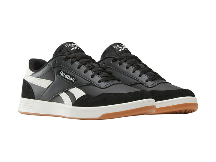 Tenis Reebok Court Advance color negro con detalles en blanco y suela de goma color miel.