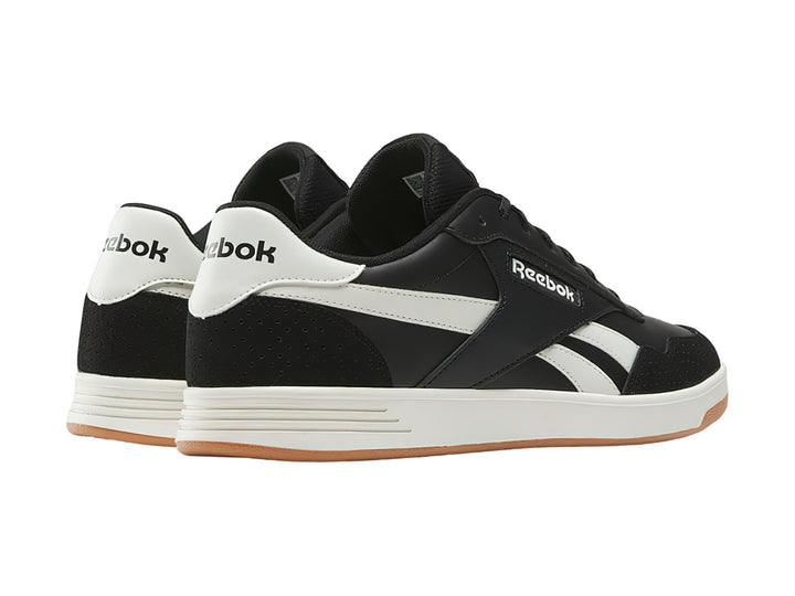Tenis Reebok Court Advance color negro con detalles en blanco y suela de goma color miel.