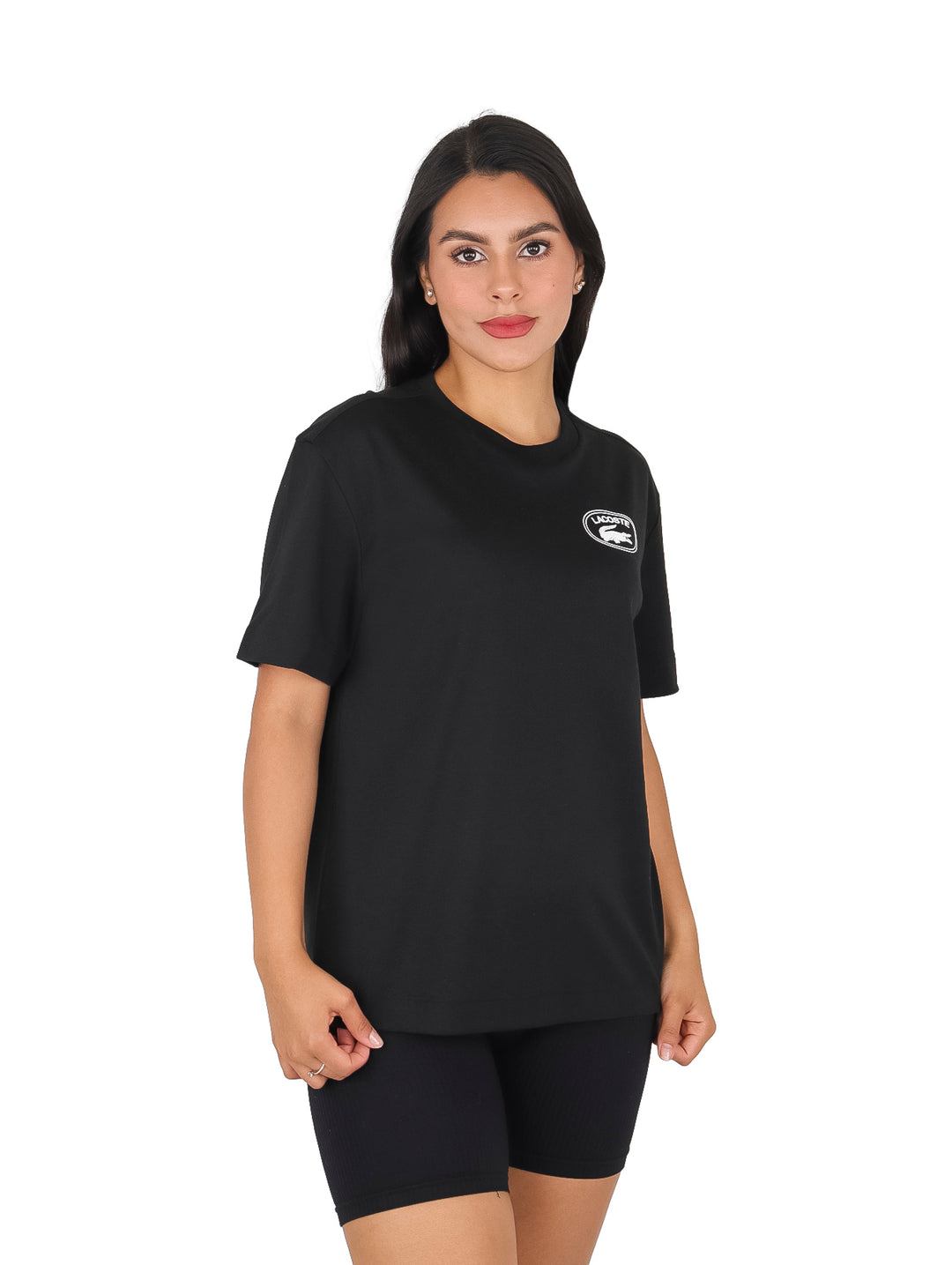 Mujer vistiendo blusa básica negra de manga corta marca Lacoste y shorts negros sobre fondo blanco.