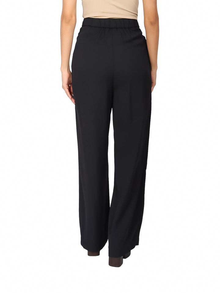 Pantalón negro de pierna ancha con detalles de remaches blancos en la cintura.