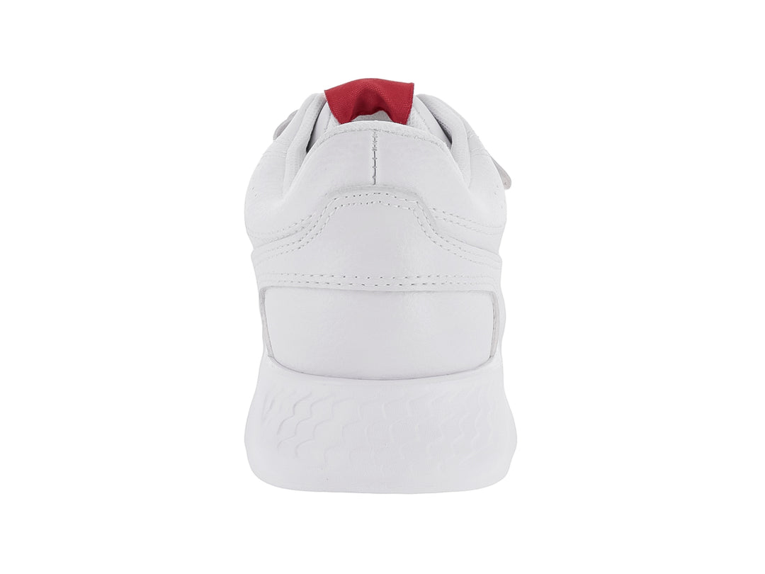 Zapato deportivo blanco para niño con cierre de velcro y suela blanca robusta.