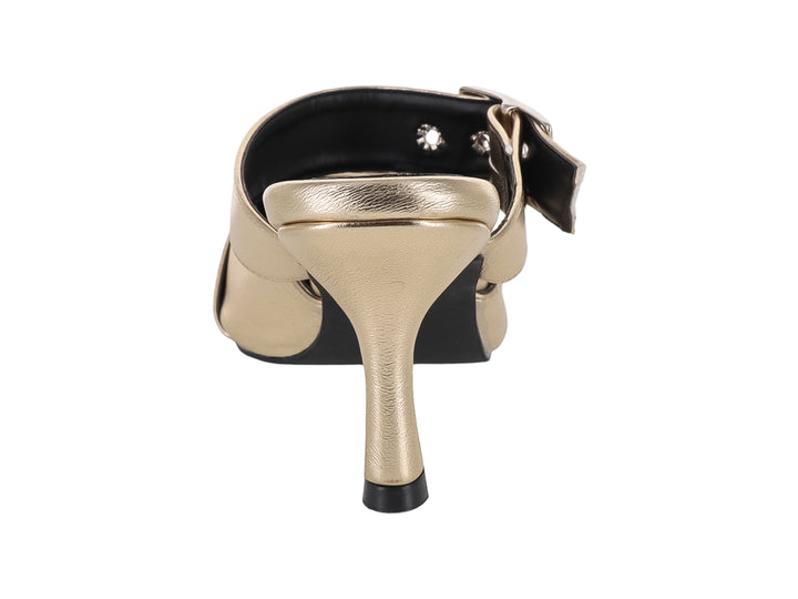 Sandalia mule color oro metálico con punta fina, tacón y hebillas decorativas.