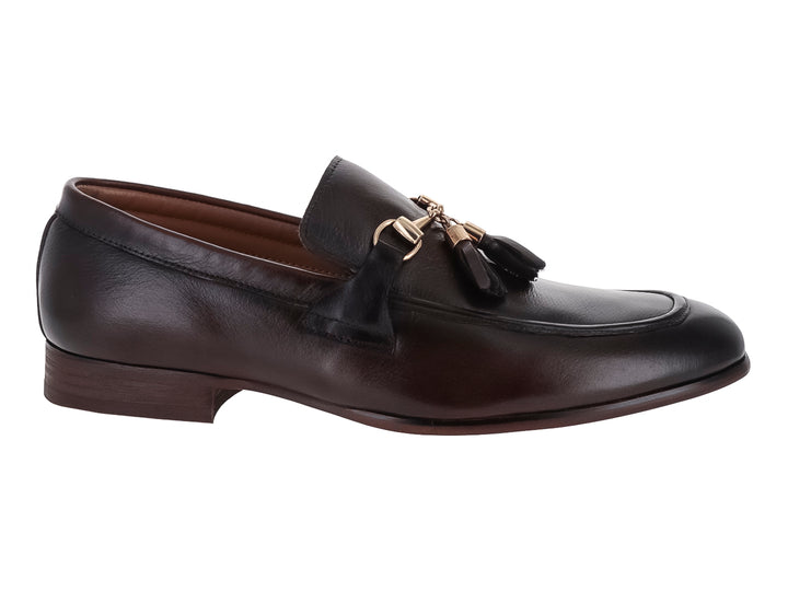 Zapato mocasín de cuero marrón con borlas y detalle metálico dorado.