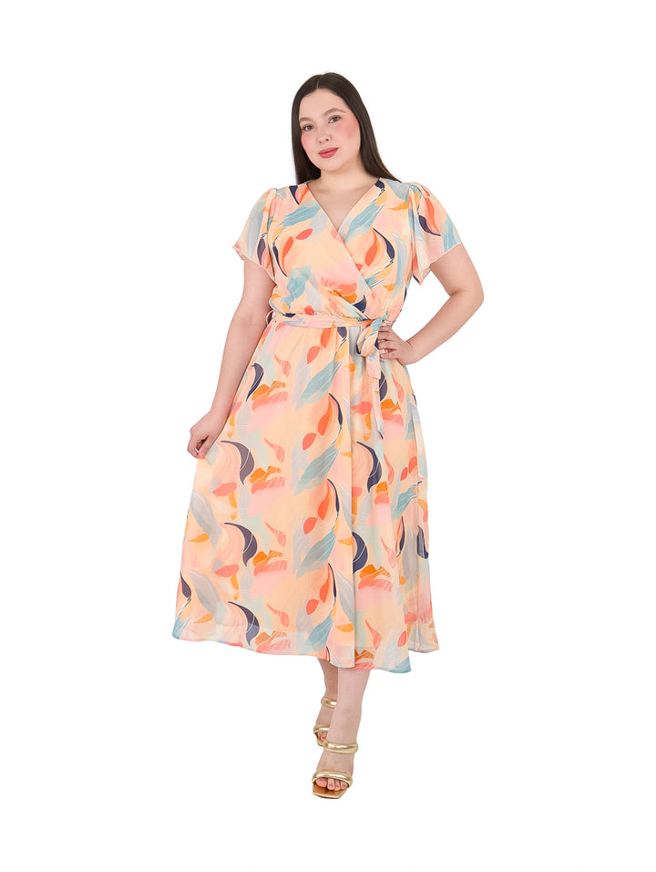 Mujer vistiendo un vestido midi color nude con estampado abstracto en tonos azul y naranja.