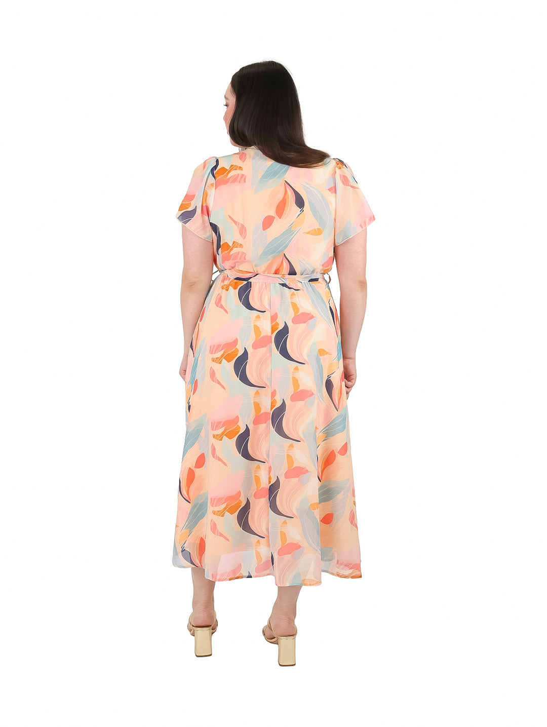 Mujer vistiendo un vestido midi color nude con estampado abstracto en tonos azul y naranja.