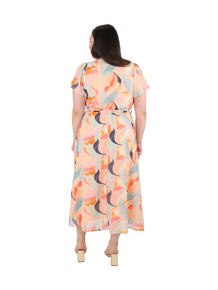 Mujer vistiendo un vestido midi color nude con estampado abstracto en tonos azul y naranja.