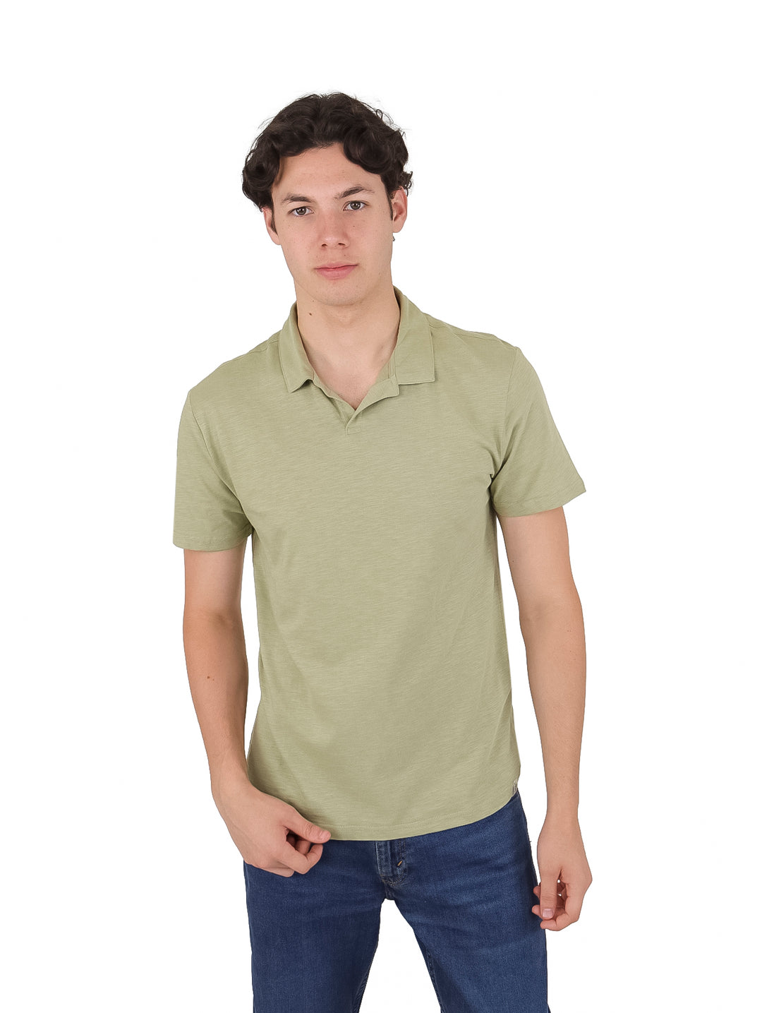 Hombre vistiendo una camiseta polo de color verde claro y pantalones vaqueros azules.