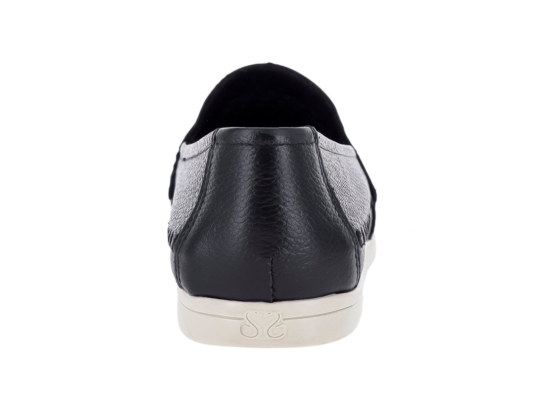 Zapato plano estilo mocasín color negro con detalles perforados y suela blanca.
