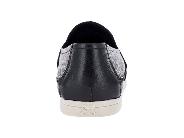 Zapato plano estilo mocasín color negro con detalles perforados y suela blanca.