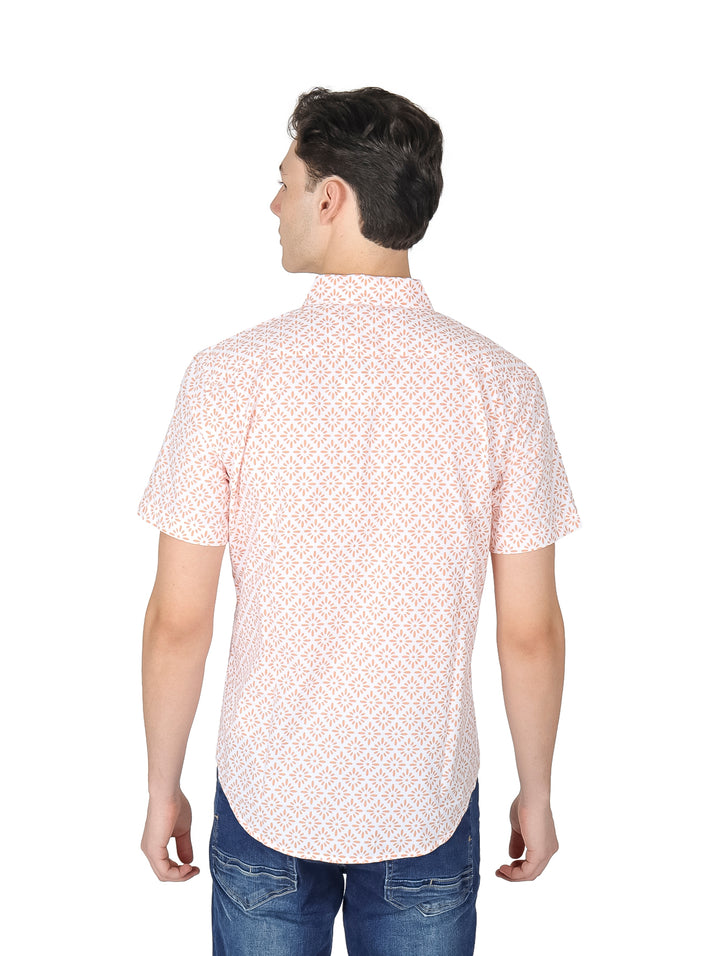Hombre vistiendo camisa de manga corta blanca con estampado pequeño en color durazno y pantalones vaqueros azules.
