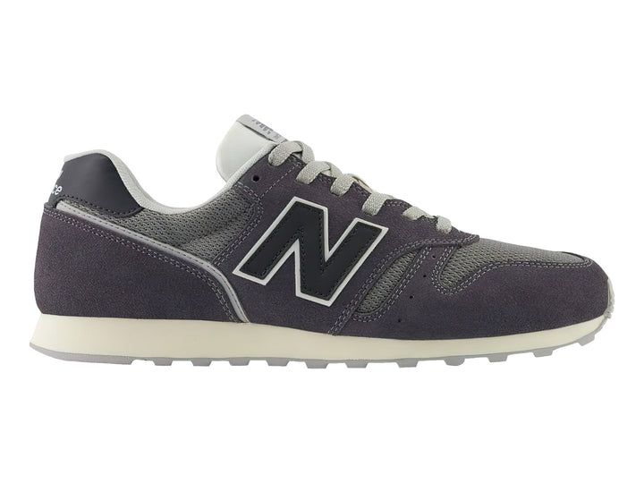 Tenis New Balance color gris oscuro con detalles en malla y suela blanca.