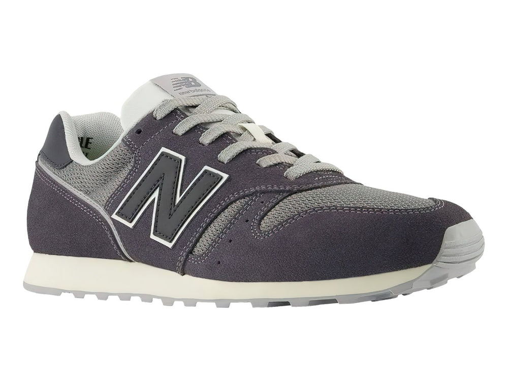 Tenis New Balance color gris oscuro con detalles en malla y suela blanca.
