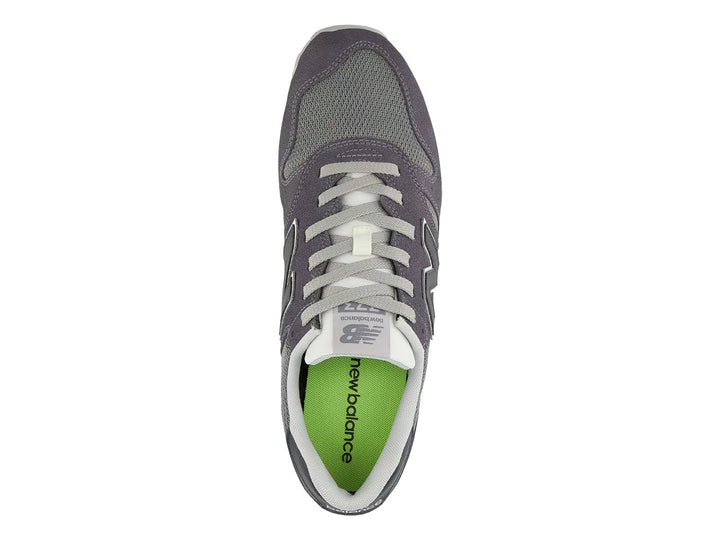 Tenis New Balance color gris oscuro con detalles en malla y suela blanca.