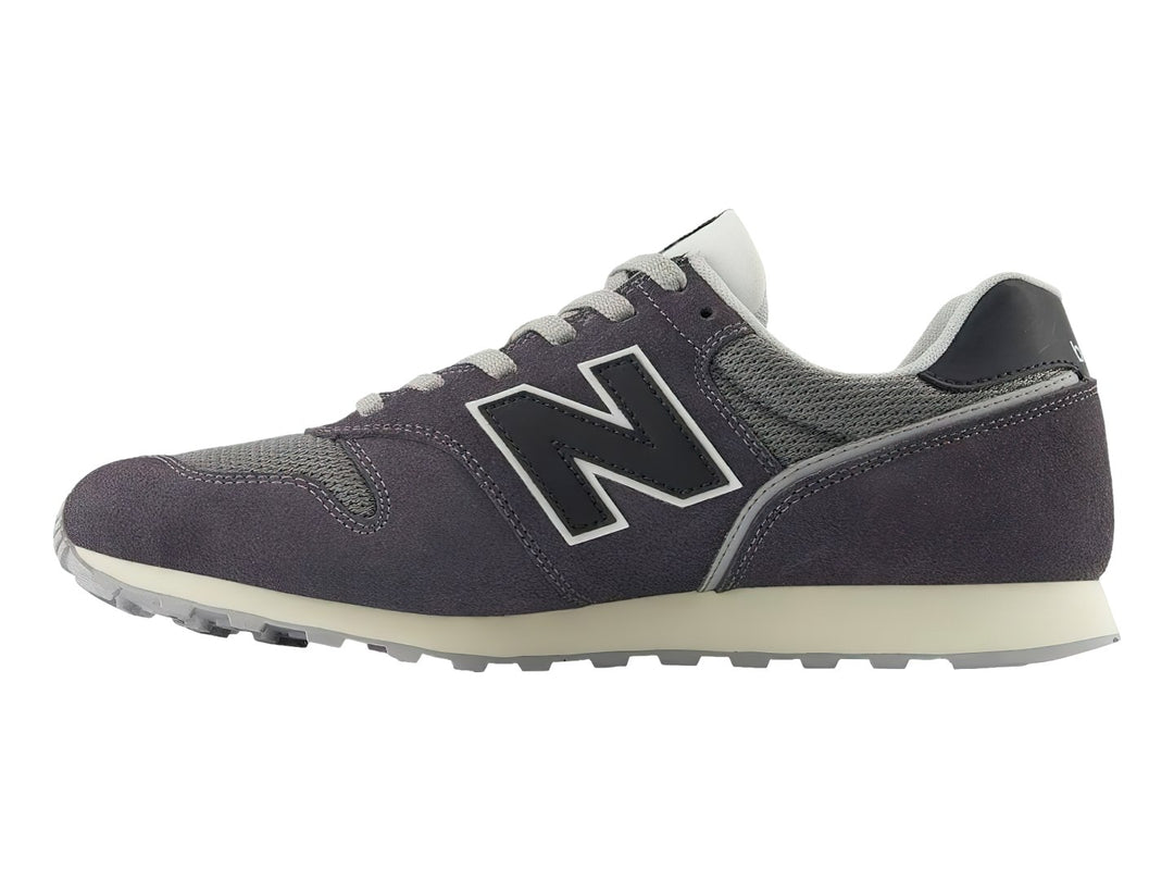 Tenis New Balance color gris oscuro con detalles en malla y suela blanca.