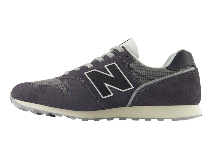 Tenis New Balance color gris oscuro con detalles en malla y suela blanca.