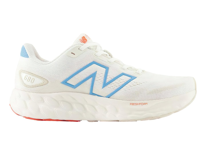 Tenis New Balance 680 color blanco con detalles en azul y suela roja.