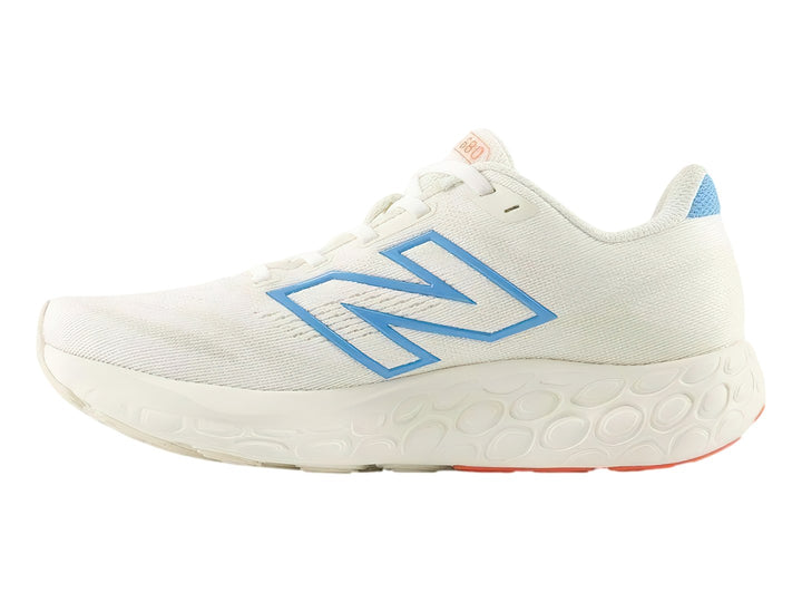 Tenis New Balance 680 color blanco con detalles en azul y suela roja.