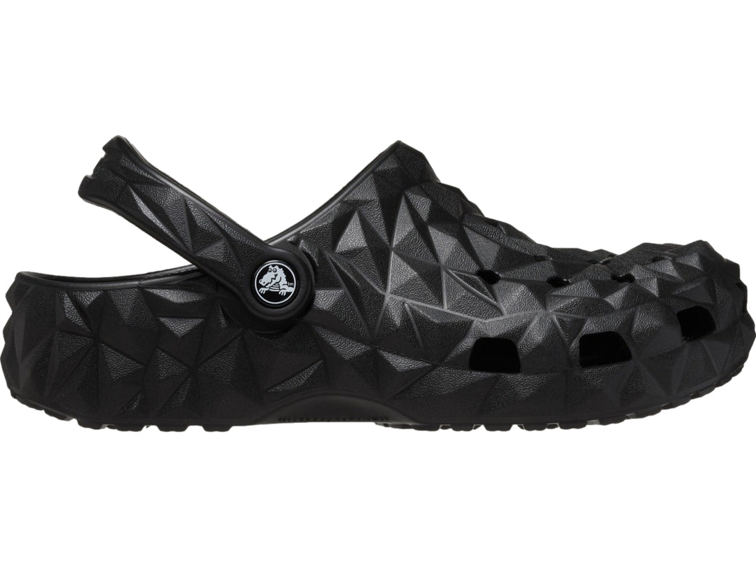 Zueco Crocs negro con relieve geométrico facetado y correa trasera ajustable.