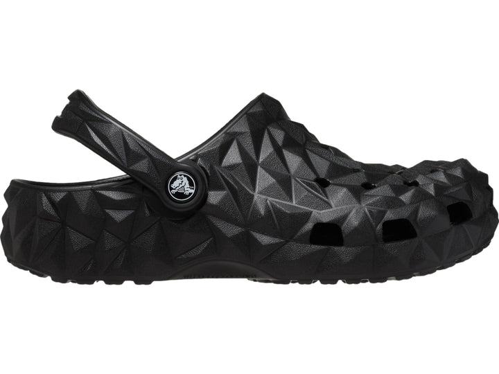 Zueco Crocs negro con relieve geométrico facetado y correa trasera ajustable.