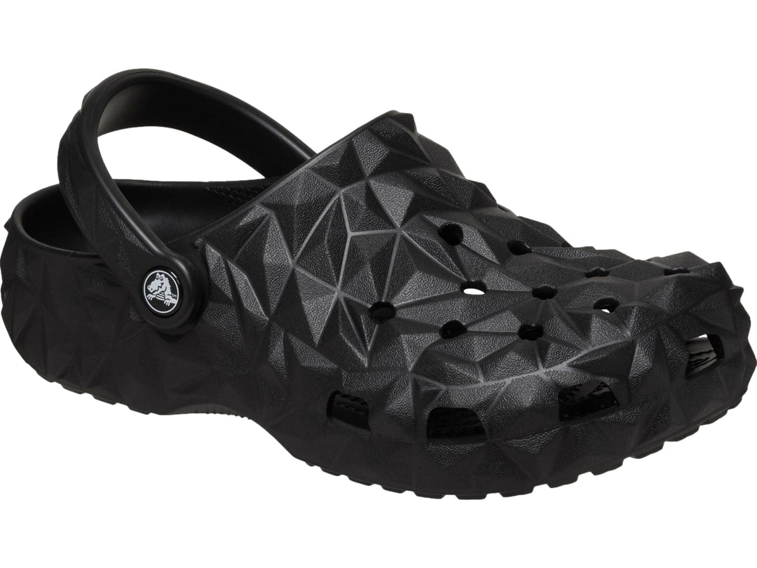 Zueco Crocs negro con relieve geométrico facetado y correa trasera ajustable.