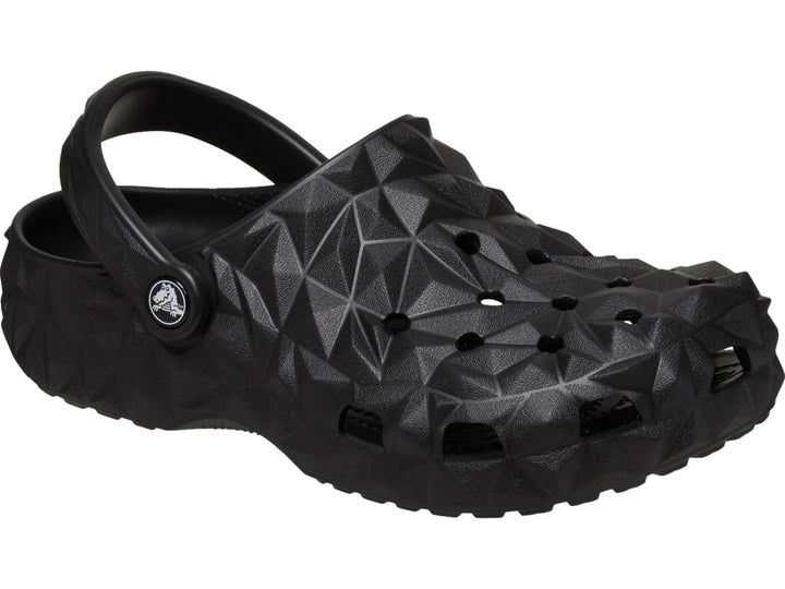 Zueco Crocs negro con relieve geométrico facetado y correa trasera ajustable.
