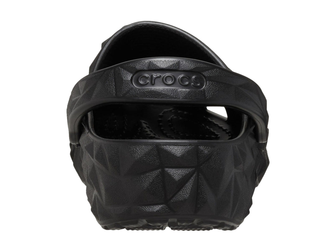 Zueco Crocs negro con relieve geométrico facetado y correa trasera ajustable.
