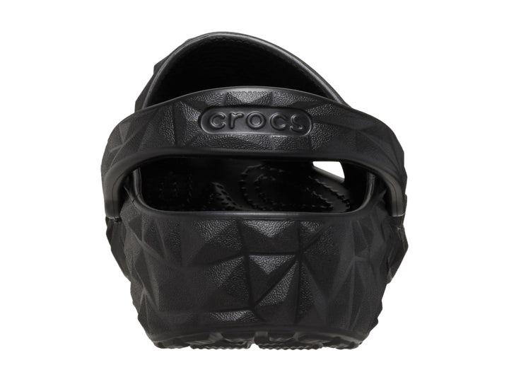 Zueco Crocs negro con relieve geométrico facetado y correa trasera ajustable.
