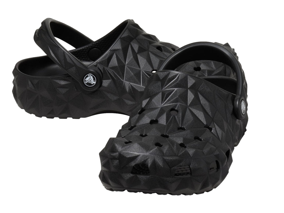 Zueco Crocs negro con relieve geométrico facetado y correa trasera ajustable.