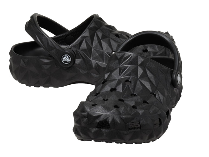 Zueco Crocs negro con relieve geométrico facetado y correa trasera ajustable.