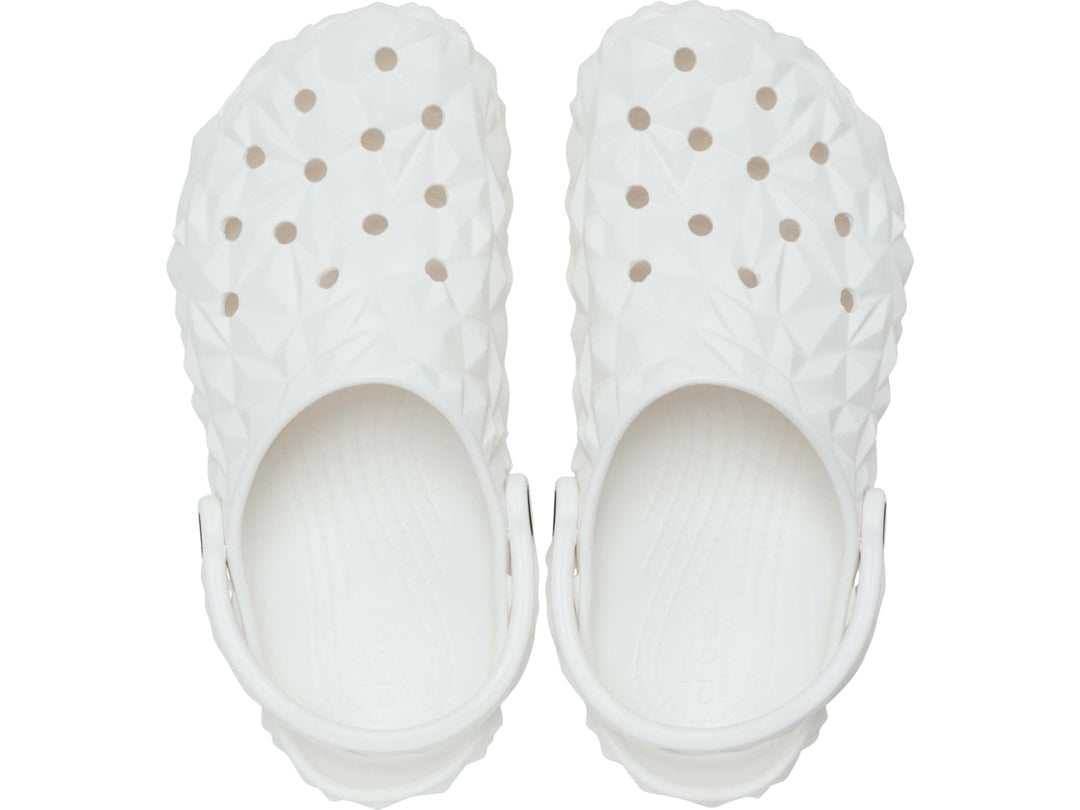 Zueco blanco Crocs con relieve geométrico facetado y correa ajustable trasera.