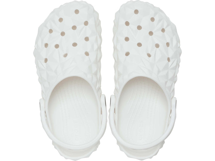 Zueco blanco Crocs con relieve geométrico facetado y correa ajustable trasera.