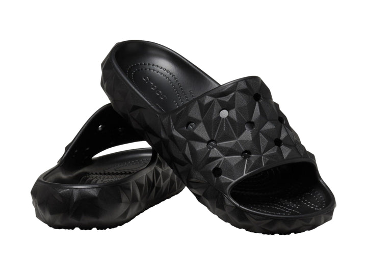 Sandalia Crocs Classic Geometric Slide en color negro con diseño de relieve geométrico tridimensional.