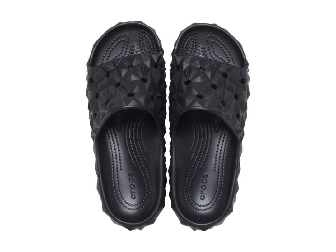 Sandalia Crocs Classic Geometric Slide en color negro con diseño de relieve geométrico tridimensional.