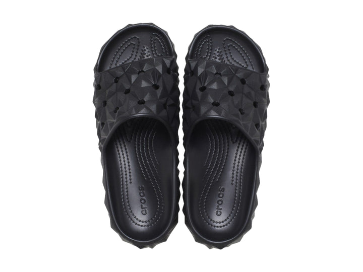 Sandalia Crocs Classic Geometric Slide en color negro con diseño de relieve geométrico tridimensional.
