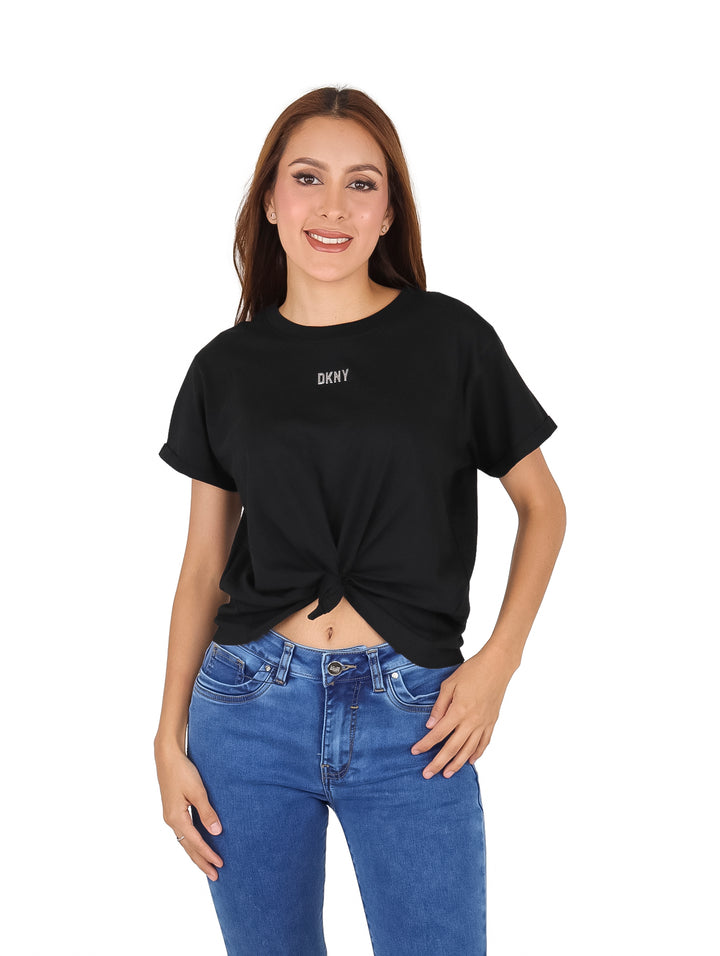 Mujer vistiendo una camiseta negra de manga corta con logo DKNY y detalle de nudo en la cintura.