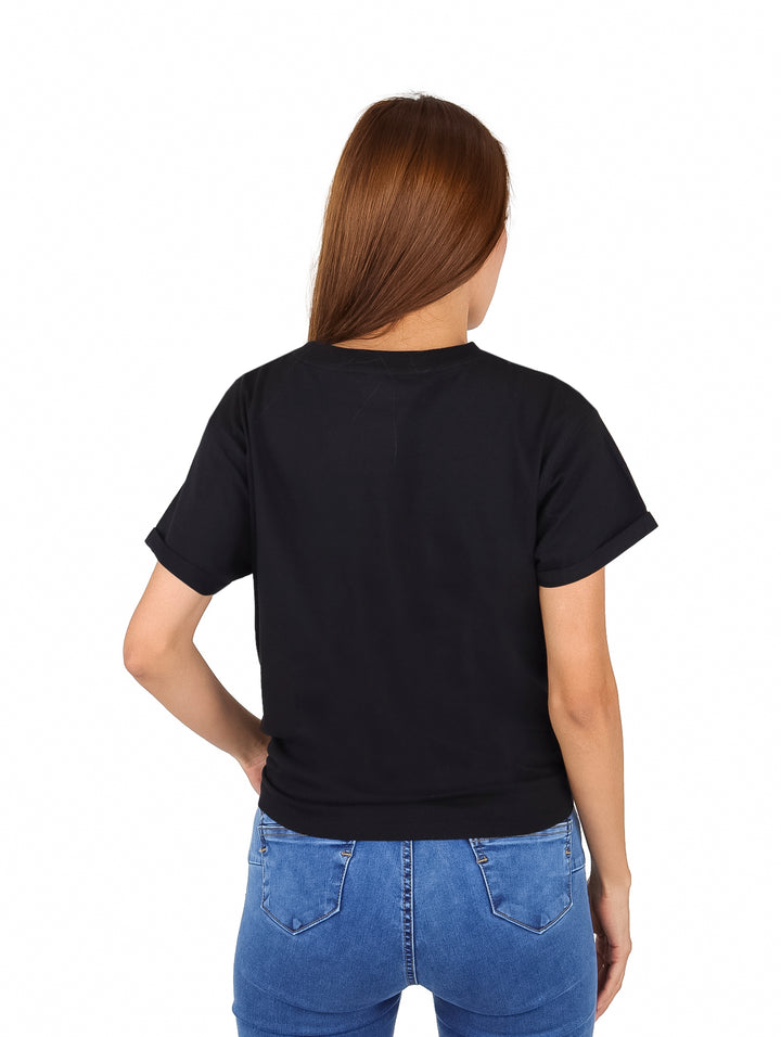 Mujer vistiendo una camiseta negra de manga corta con logo DKNY y detalle de nudo en la cintura.