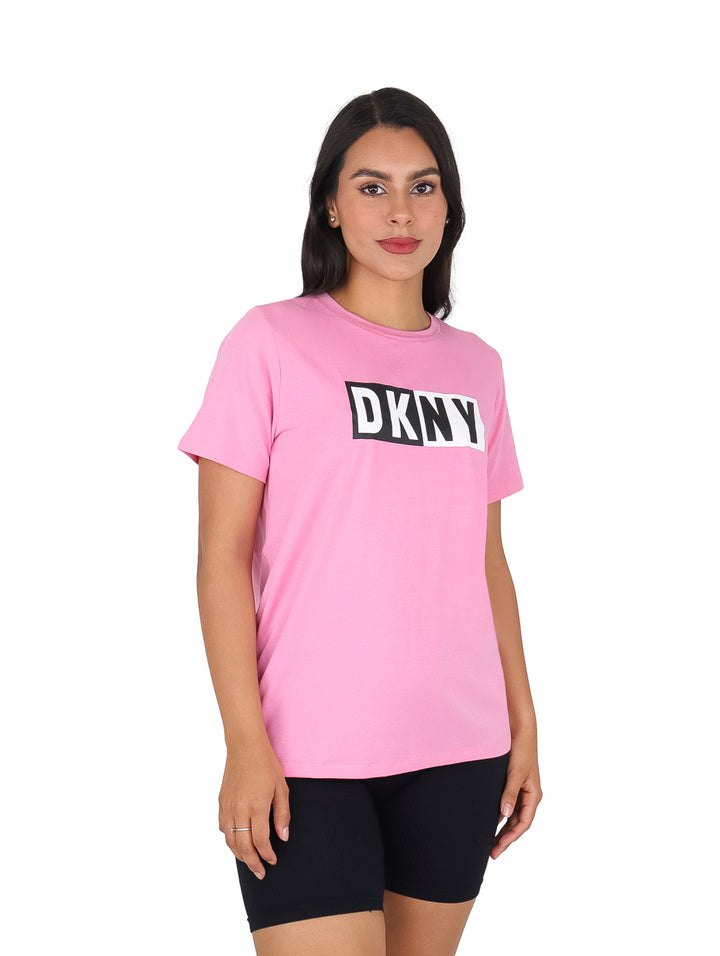 Mujer vistiendo camiseta rosa de manga corta con logotipo DKNY en negro en el pecho.