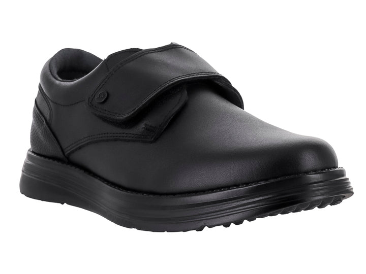 Zapato escolar negro para niño con cierre de velcro y suela negra.