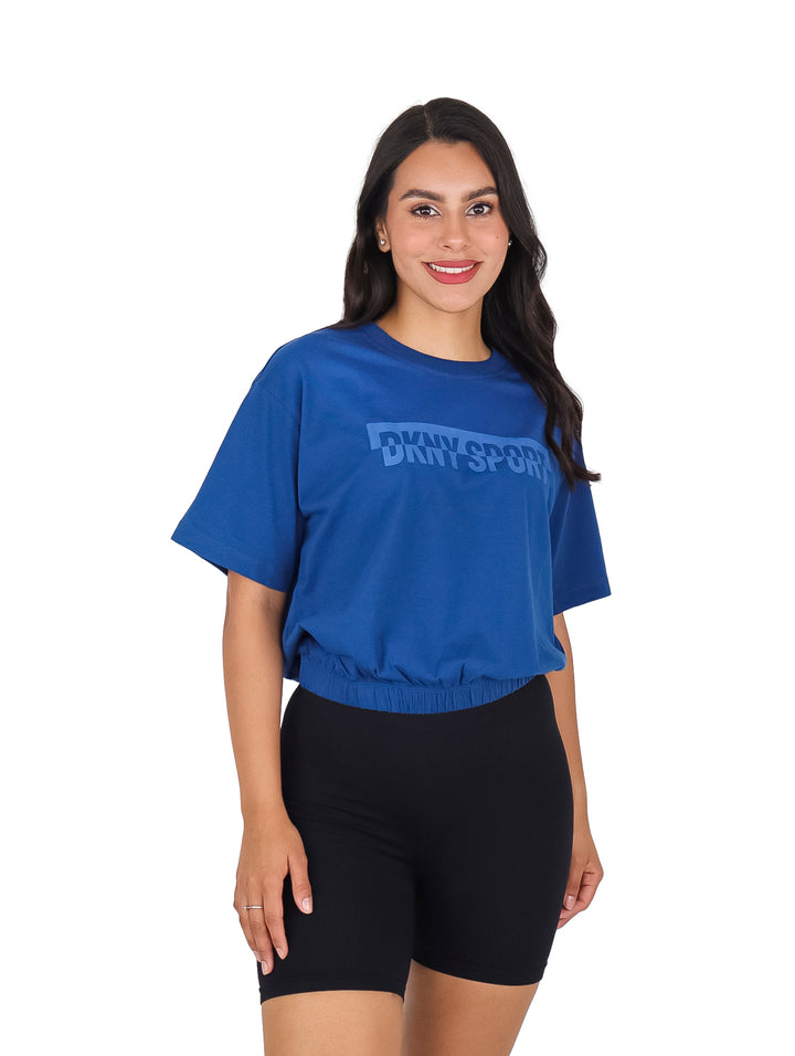 Mujer vistiendo camiseta azul de manga corta DKNY Sport con ajuste en la cintura.