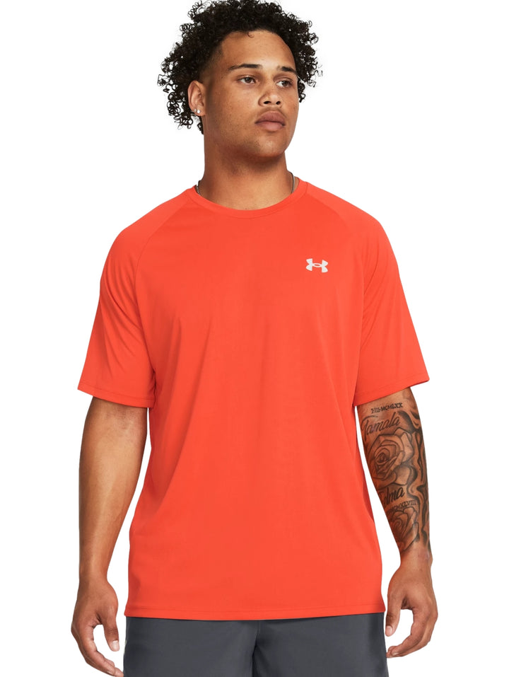 Hombre vistiendo una camiseta deportiva de manga corta color naranja con logotipo blanco en el pecho.