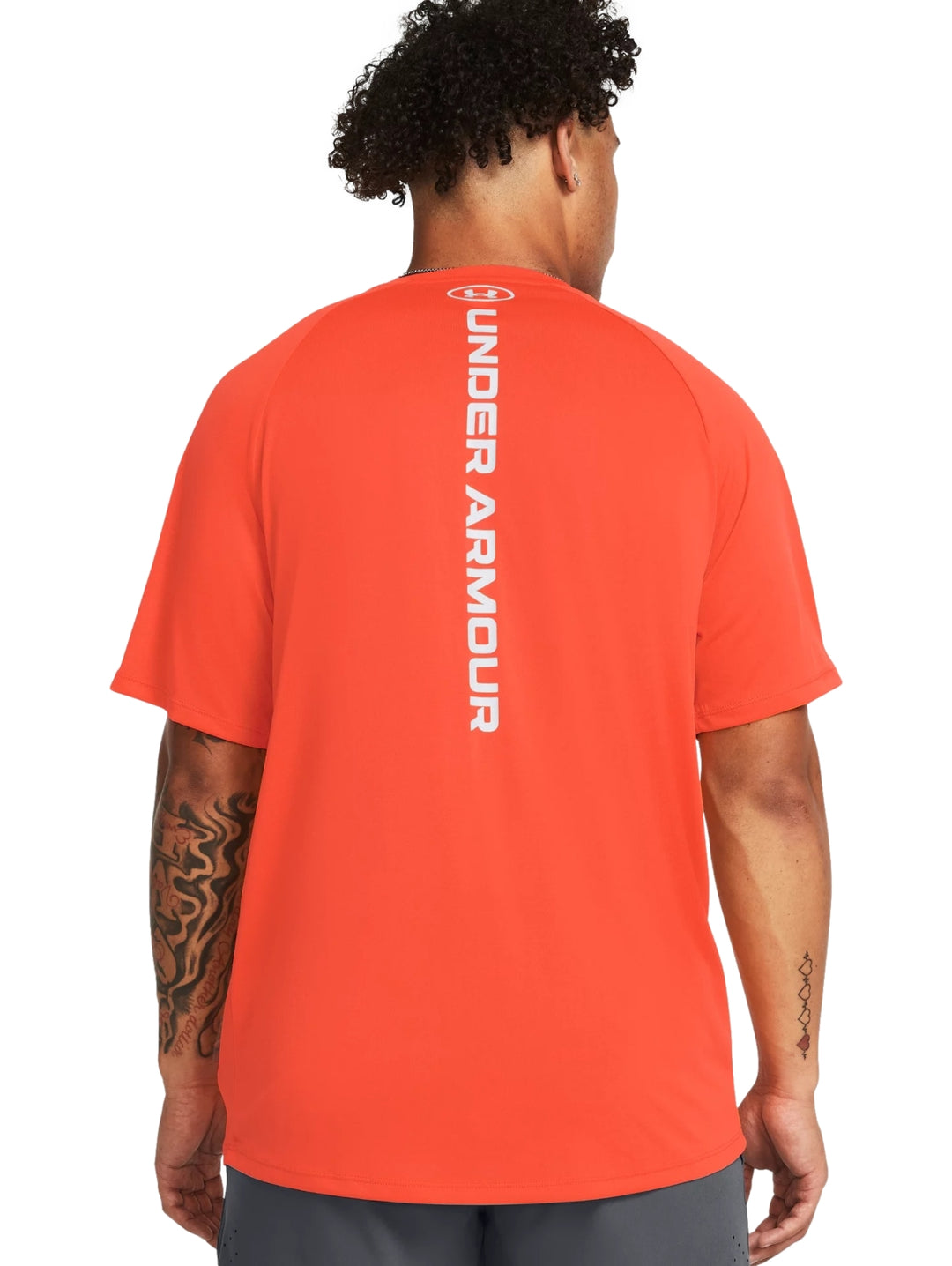 Hombre vistiendo una camiseta deportiva de manga corta color naranja con logotipo blanco en el pecho.